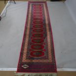 A Turkish red ground silk runner, with signed border, 283 x 76cm