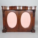 A Victorian mahogany serpentine-front credenza with 2 glazed panelled doors, and applied carved