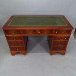 A reproduction yew wood twin-pedestal writing desk, with tooled and embossed green leather skiver,