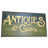 A painted and gilded wood sign "Antiques and Curiosities", width 110cm