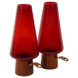 A pair of mid-century Danish chamber sticks of stylised design, with tapered red glass shades and