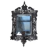 A pierced and engraved cast-metal bevel-edge wall mirror, with single sconce and decorated with