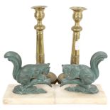 A pair of verdigris metal squirrels on plinths, and a pair of embossed brass candlesticks, 25cm