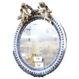 A porcelain framed oval wall mirror, surmounted by angels, height 32cm