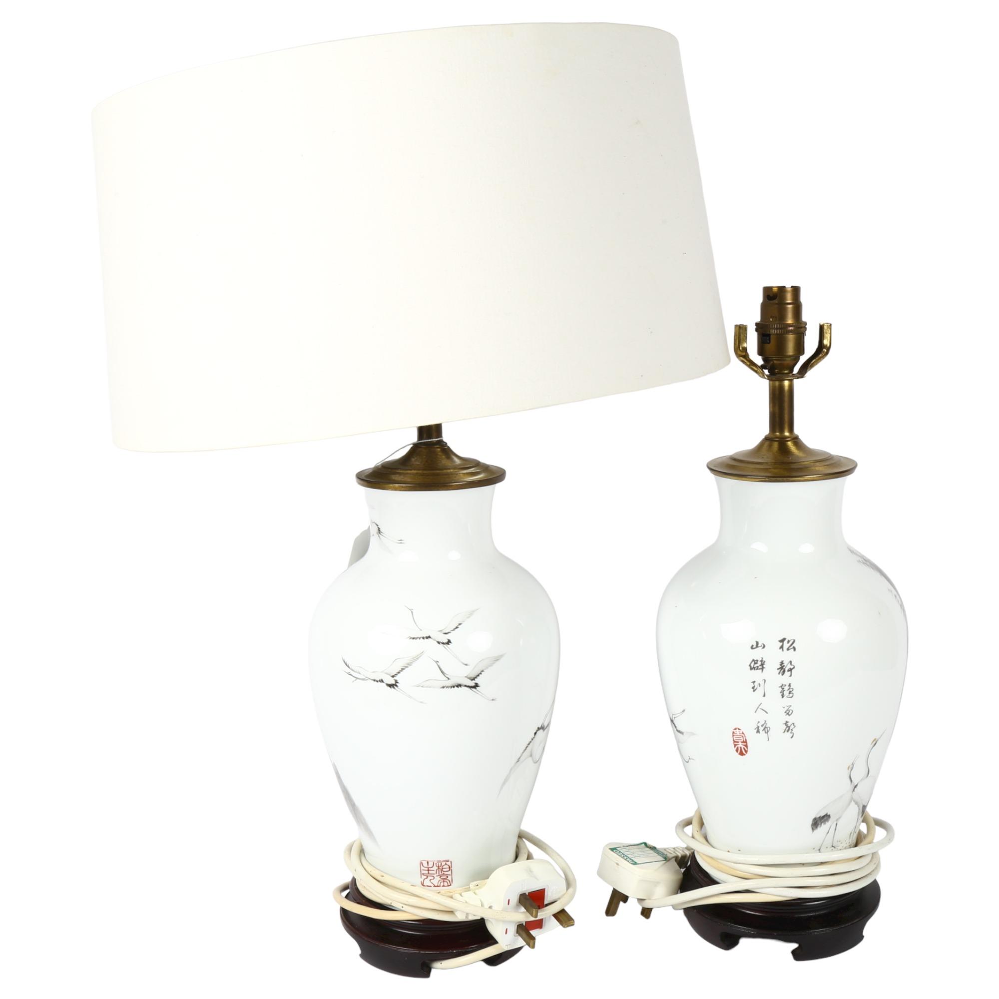 A pair of Japanese porcelain table lamps, with design of mountains and cranes, with matching white