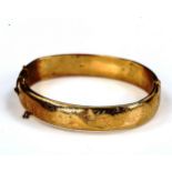 A mid-20th century 9ct gold hinged bangle, engraved foliate decoration, maker's marks C and F,