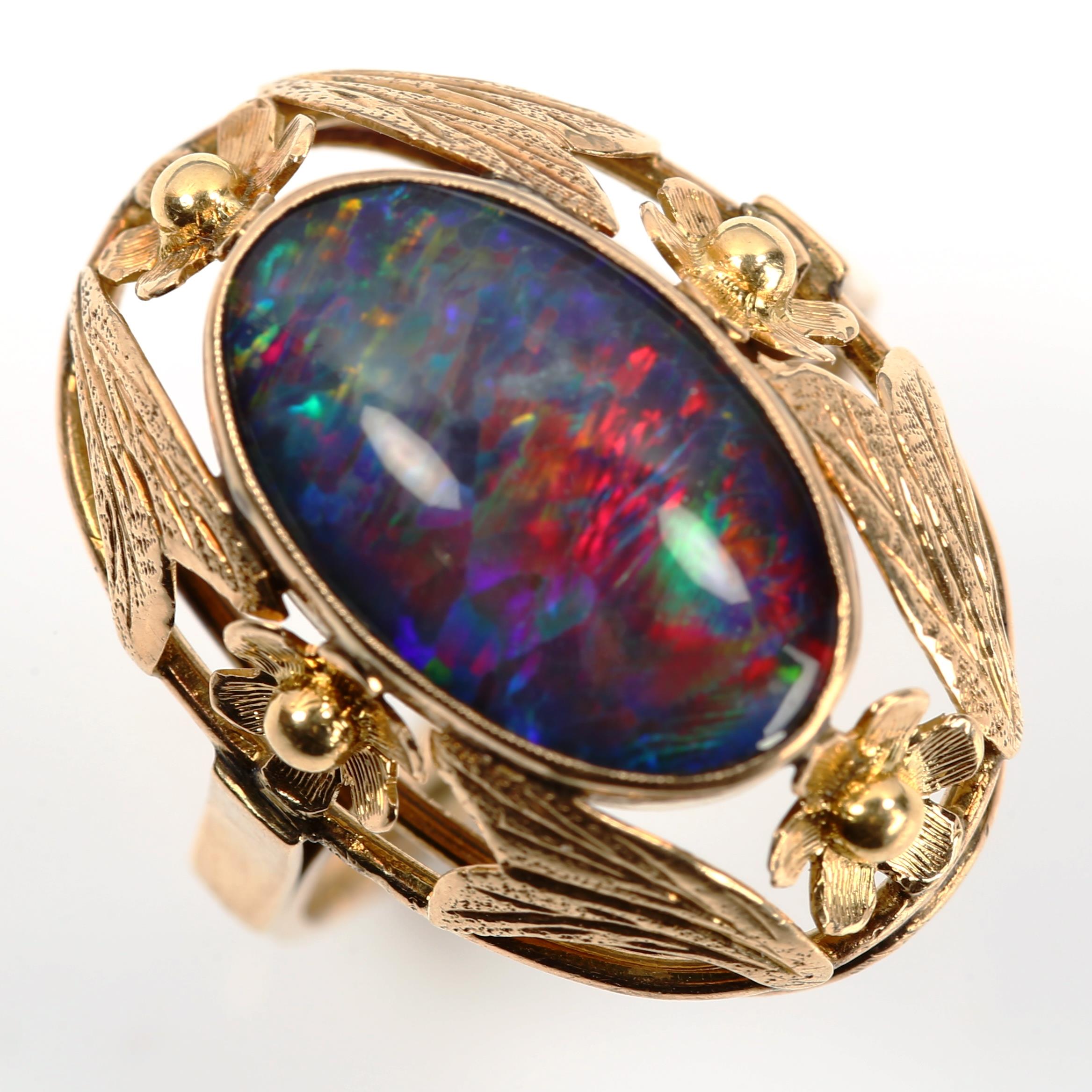 A large Continental black opal doublet dress ring, unmarked gold settings with floral bezel, setting