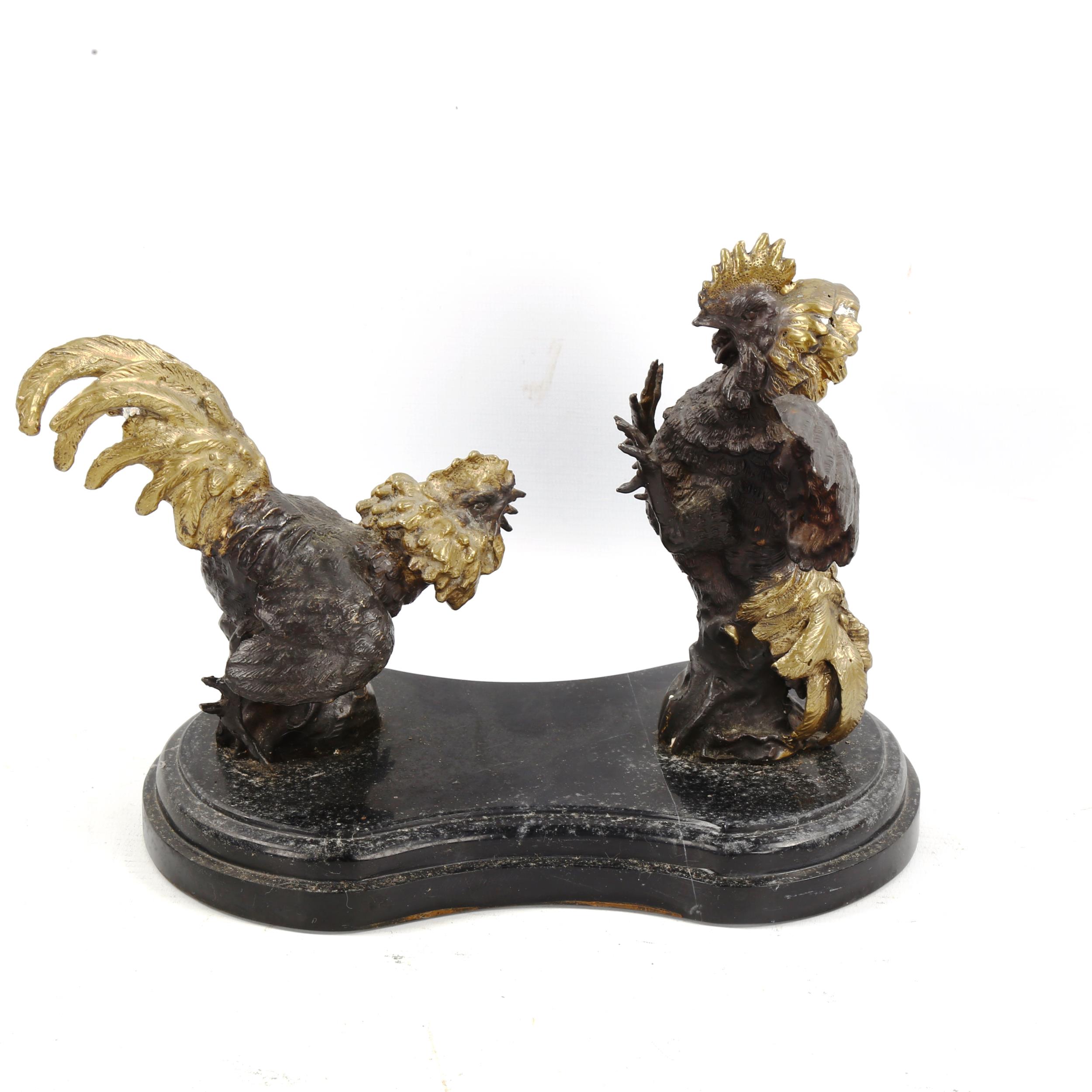 A contemporary parcel gilt and patinated bronze sculpture of fighting cockerels, on shaped marble