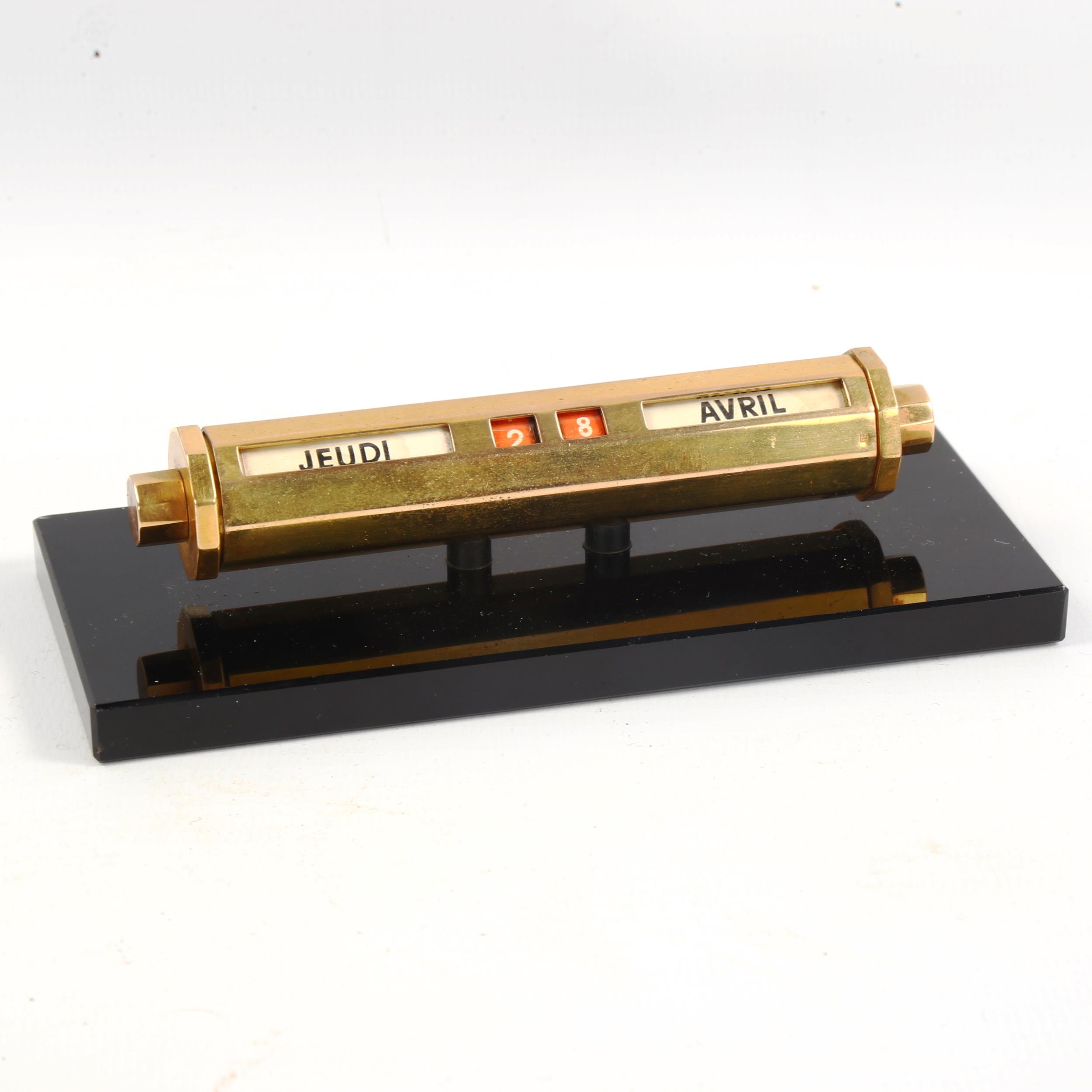 A French mid-century brass desk calendar on black glass base, length 14cm