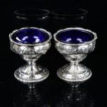 A pair of George III Irish silver pedestal salt cellars, with blue glass liners and relief