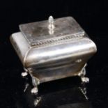 An Edwardian silver sarcophagus tea caddy, spiral finial with gadrooned rim and lion paw feet, by