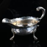 A George II silver sauce boat, with a scalloped rim, scrolled acanthus leaf handle and hoof feet, by