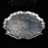 An Edwardian silver salver, circular form with scalloped rim and hoof feet, by Charles Stuart Harris