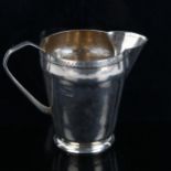 An Arts and Crafts style silver cream jug, plain tapered cylindrical form, with hand engraved rim