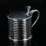 A George V silver drum mustard pot, pierced decoration with thumbpiece and blue glass liner, by