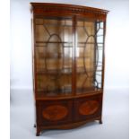 An Edwardian inlaid mahogany bow-front display cabinet in Sheritan style, with carved cornice and