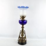 An Art Neuveau oil lamp with blue glass well and shade, height 76cm some wear to metal surfaces,