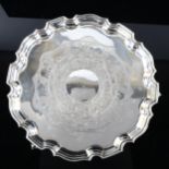 A George V silver salver, circular form with scalloped rim and Indian inspired engraved animal