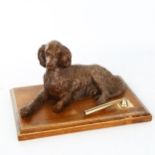 A carved wood desk stand surmounted by a reclining dog, early 20th century, length 25cm Good