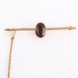 An early 20th century garnet bar brooch, unmarked rose gold settings with oval mixed-cut garnet,