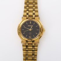 GUCCI - a lady's gold plated 9200L quartz bracelet watch, black dial with gilt baton hour markers,
