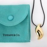 TIFFANY & CO - an 18ct gold Feather pendant necklace, by Elsa Peretti, on black cord, hallmarks