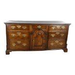 18th century oak dresser base with arch panelled centre cupboard and 7 drawers, length 178cm,