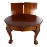 A circular mahogany wind-out dining table, circa 1900, with carved edge and ball and claw feet, 2