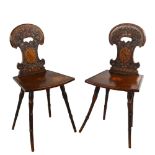 A pair of 19th century Swiss hall chairs, with ornate relief carved backs and inlaid panels, part of