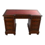 A mahogany inverted break-front pedestal desk, with inset leather top and carved frieze drawers,