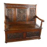 An Antique oak settle with relief carved rose design 3-panel back, rising seat and carved 2-panel