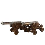 A pair of 19th century bronze-barrelled model cannons, on wheeled cast-iron dragon design bases,