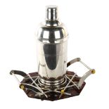 A French Art Deco electroplate cocktail shaker, on simulated tortoiseshell and silver plate stand