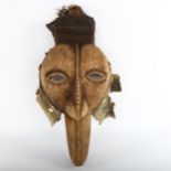 An African carved wood Tribal mask, with textile and shell surround and feather plumage, height 52cm
