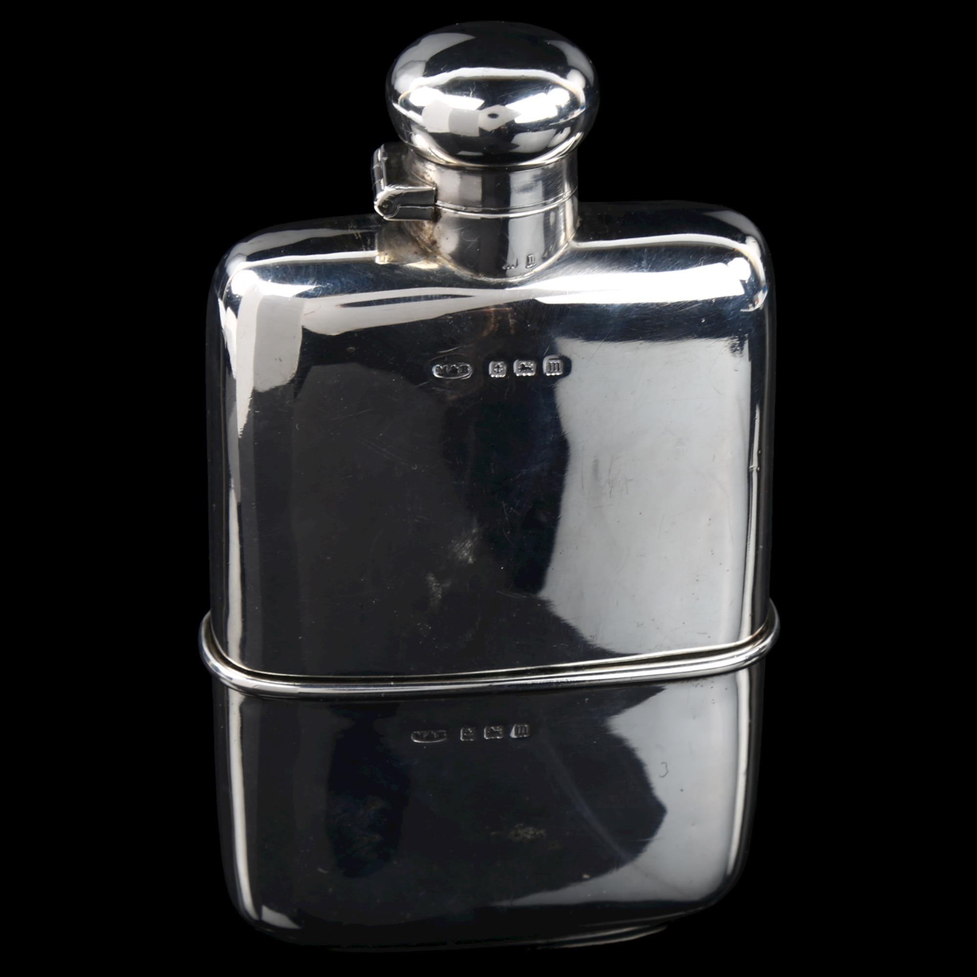 A George V curved silver spirit flask, with screw-lock button cap and removeable beaker with gilt