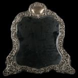A large Edwardian silver-fronted shaped dressing table strut mirror, relief embossed foliate