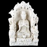 A Chinese blanc de chine porcelain figure of Buddha in a cave flanked by attendant figures,