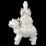 A Chinese blanc de chine porcelain figure of Buddha riding a Dog of Fo, impressed seal marks on