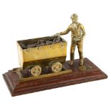 A cast-brass coal mining figure and carriage on wood plinth, length 23cm Good condition