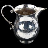 An Art Deco George V silver baluster cream jug, hand planished decoration with scroll handle, by