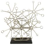 A 1960s' brutalist snowflake sculpture of sketetal form on an ebonised wood base, inscription to