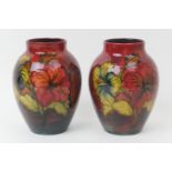 Pair Moorcroft flambe hibiscus vases, ovoid form, decorated in rich red with a shaded blue ground,