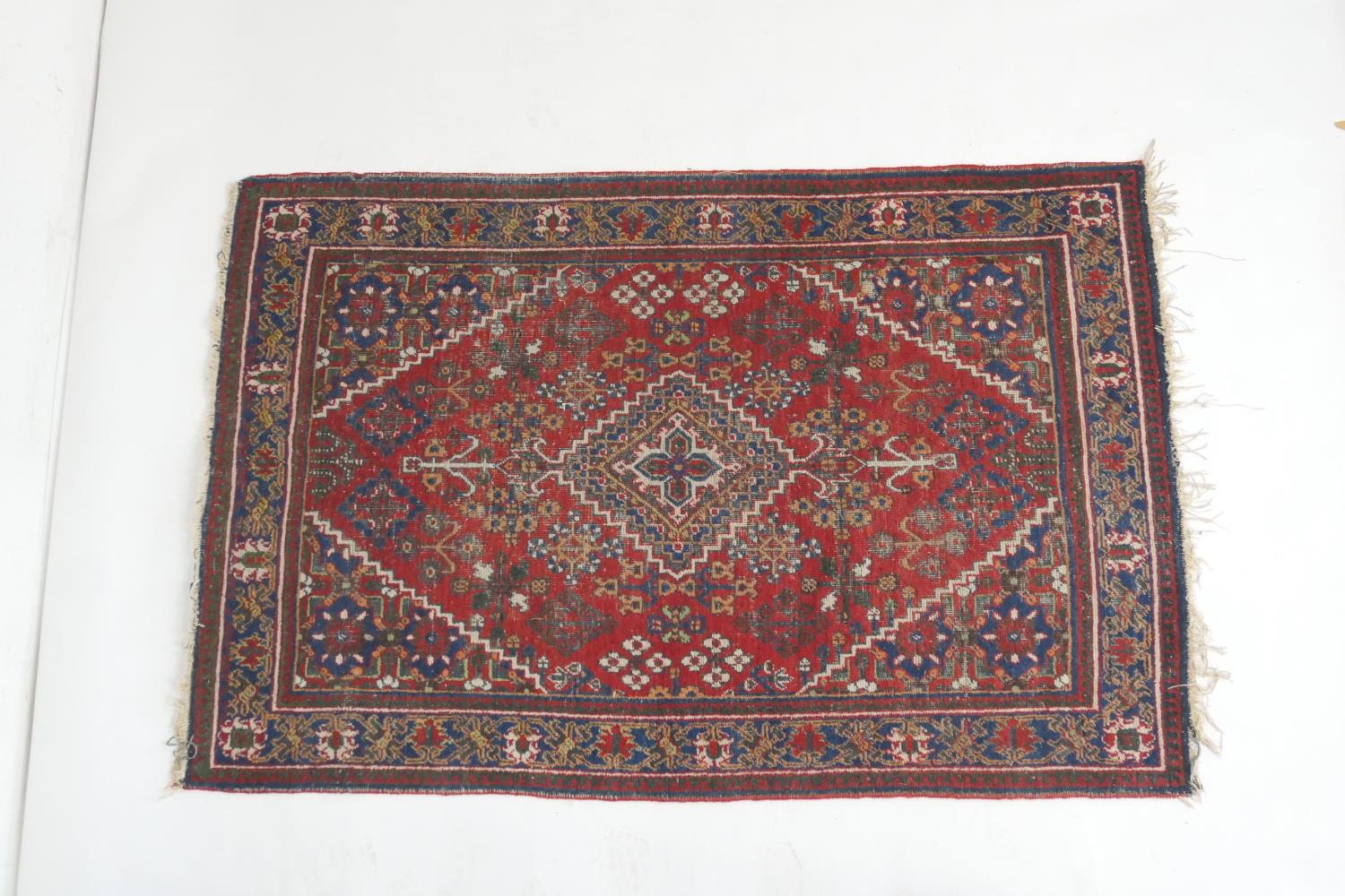 Persian woollen rug, centred with a pole medallion against a red ground with blue flowerhead