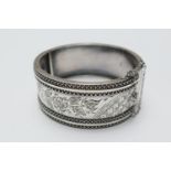 Victorian silver hinged bangle, in the Aesthetic taste, Birmingham 1883, chased with flowerhead,