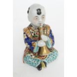 Japanese Kutani porcelain model of a boy playing a horn, Meiji (1868-1912), decorated in rich