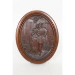 Flemish carved walnut oval plaque, detailed in low relief with a couple walking within an urban