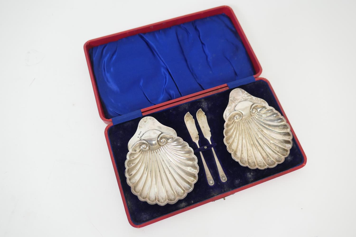 Cased pair of silver shell form butter dishes, Sheffield 1911, complete with butter knives, gross