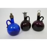 Three coloured claret flasks, in blue and dark amethyst, all with metal mounts, heights 20.5cm -