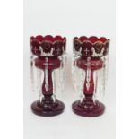 Pair of Victorian ruby glass lustres, with crenellated tops enamelled with floral garlands and