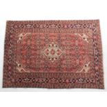 Hamadan woollen rug, salmon pink field centred with a fawn medallion within deep blue borders,